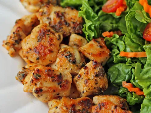 Healthy Garlic Lemon Chicken Bites, seasoned and grilled to perfection, served with a fresh green salad with cherry tomatoes and shredded carrots.